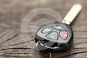 Car keys with remote control alarms on wooden background.