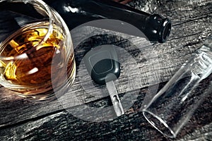 Car keys on the table with alcohol drink, fallen flask and fallen glass, drive under alcohol influence concept