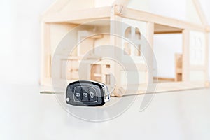 Car keys with wooden house model on background. Choice of byuing basic need. Decision of priority or primary necessity