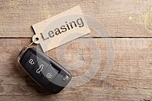 Car Leasing concept. Vehicle security key with tag on the wooden background