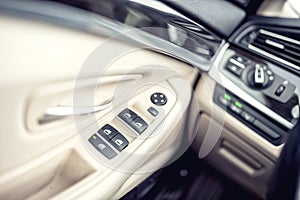 car leather interior details of door handle with windows controls and adjustments.