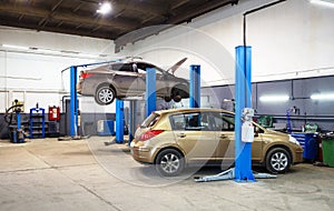 Car on lift in mechanic shop or garage, interior of auto repair workshop, vehicles inside maintenance
