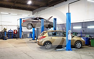 Car on lift in mechanic shop or garage, interior of auto repair workshop, vehicles inside maintenance photo