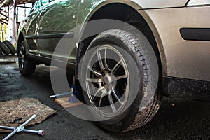 Car lifted by scissor jack without wheel outdoors, closeup. Tire puncture