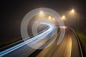 Car light trails rounding a corner into the mist