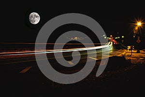 Car lights and giant moon