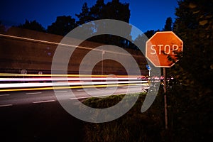 Car lights on the highway with stop sign on the edge of the road