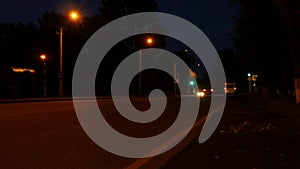 Car lights in nighttime on a crossroad with traffic light, low traffic on an motorway junction