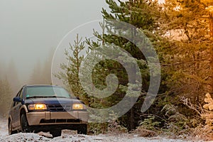 Car with lights on a snow covered road.