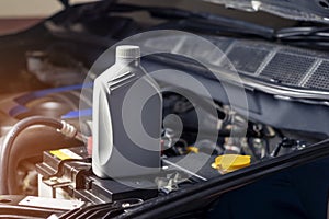 Car lubricant gallon or from gray bottle on engine background Oil change service, auto repair shop Technology and transportation