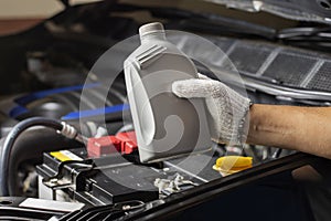 Car lubricant gallon or from gray bottle on engine background Oil change service, auto repair shop Technology and transportation