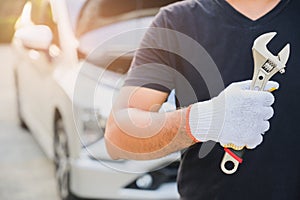 Car machanic holding wrench near car. Car maintenance concept