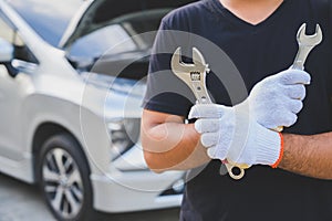 Car machanic holding wrench near car. Car maintenance concept