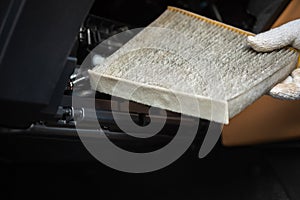 Car maintenance and repair concept. Man removing the dirty car air conditioner filter for cleaning or replace