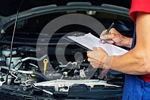 Car maintenance and repair - mechanic writing checklist paper on clipboard