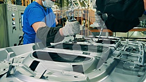 Car manufacturing workers using structural adhesive at a car factory