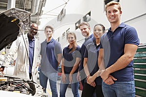 Car mechanic and apprentices in a garage looking to camera photo