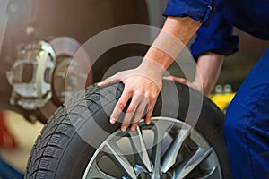 Car mechanic in workshop changing tires photo