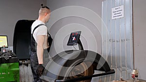 A car mechanic balances wheels on a special setup. Repair of automobile tires and rims