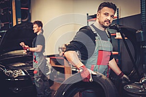 Car mechanic balancing car wheel on balancer in auto repair service.