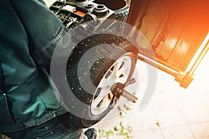 Car mechanic balancing car wheel on computer machine balancer in auto repair service