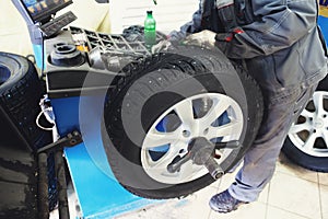 Car mechanic balancing car wheel on computer machine balancer in auto repair service