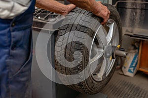 Car mechanic balancing car wheel on a computer machine balancer in auto repair service