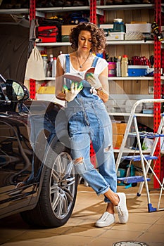 Car mechanic, woman studying the instructions for repair and adjustment of the car. Preparing for autotravel. photo