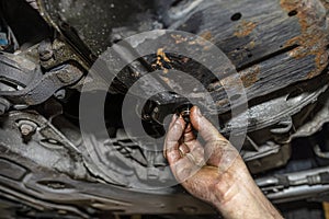 The car mechanic bolts a new screw with a copper washer to the oil sump, in a diesel engine.