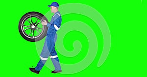 Car mechanic carrying tire in studio