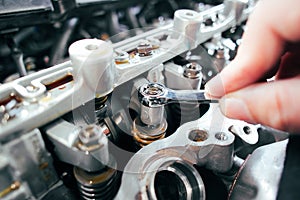 Car mechanic checking and adjusting valves of car engine