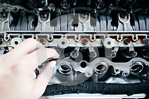 Car mechanic checking and adjusting valves of car engine