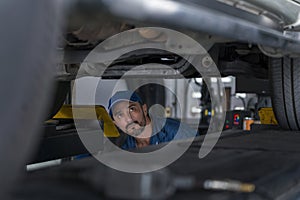 Car mechanic checking the car suspension. Mechanic man or smith repairing car at garage