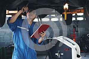 Car mechanic checking and having car transmition maintenance service at garage and service station photo