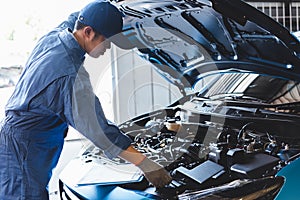 Car mechanic checking to maintenance vehicle by customer claim order in auto repair shop garage by list in clipboard. Engine