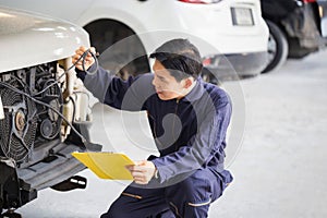 Car mechanic with a checklist, Technician checking modern car at garage, Car repair and maintenance concepts