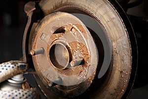 Car mechanic cleaning car wheel brake disk from rust corrosion at automobile repair service station photo