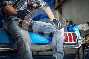 Car Mechanic with Cordless Powertool in His Hand and His Next Project