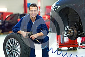 Car mechanic crouching down by a tire photo