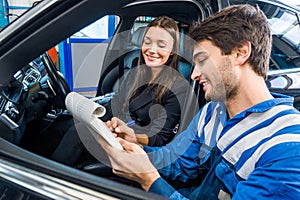Car Mechanic With Customer Going Through Maintenance Checklist