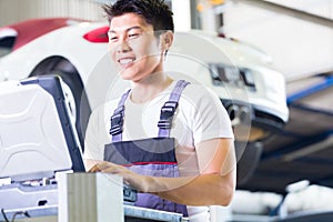 Car mechanic with diagnosis tool in Asian auto workshop