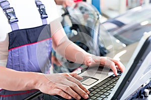 Car mechanic with diagnosis tool in auto workshop