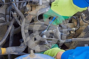 a car mechanic disassembles a car,a man repairs under the hood of a car