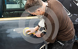 Car mechanic with dust mask grinds a car part in a service station - Serie car repair workshop