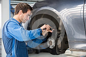Car Mechanic Examining Brake Disc With Caliper