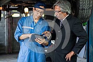 Car mechanic explaining car and engine maintenance list to customer at garage and service station