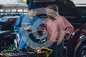 Car mechanic explaining to elder customer the maintenance list at garage and car maintenance service station