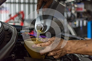 Car mechanic fills a fresh lubricant engine oil