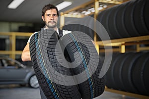Car mechanic in garage is holding tires