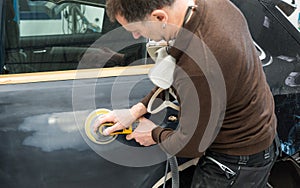 Car mechanic grinds a car part in handicraft in a service station - Serie car repair workshop